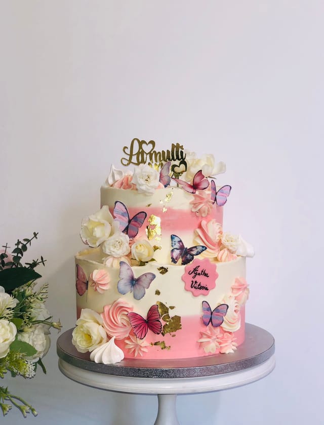 Pink celebration cake decorated with butterflies and flowers